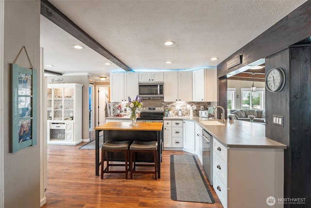1598 Tedford St SE, East Wenatchee, WA 98802 - kitchen with appliances with stainless steel finishes, white cabinetry, a textured ceiling, backsplash, and wood finished floors