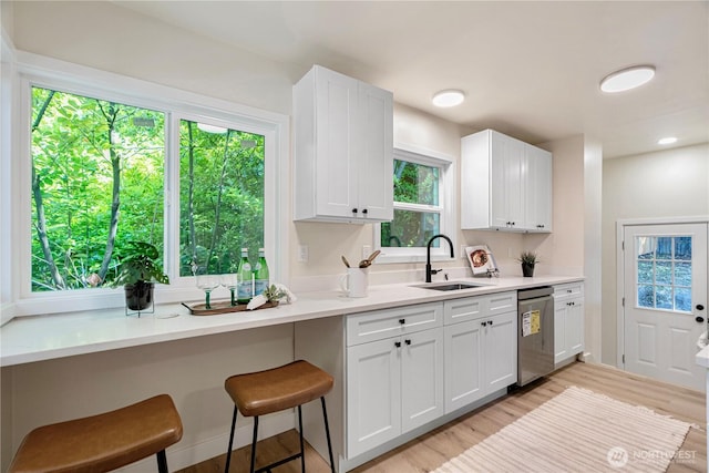 2874 30th Ave W, Seattle, WA 99819 - kitchen with dishwasher, light wood-type flooring, white cabinetry, light countertops, and a kitchen bar