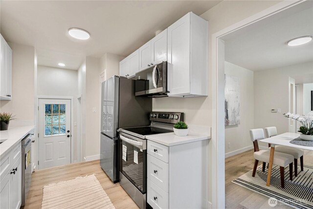 2874 30th Ave W, Seattle, WA 99819 - kitchen featuring stainless steel appliances, light wood-style floors, white cabinetry, light countertops, and recessed lighting