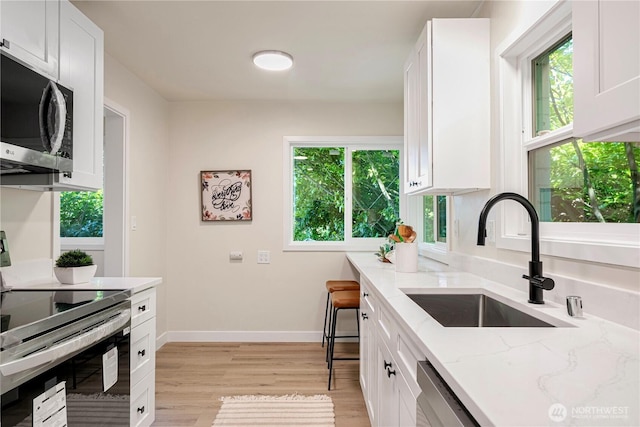 2874 30th Ave W, Seattle, WA 99819 - kitchen with appliances with stainless steel finishes, light wood-style flooring, and white cabinets