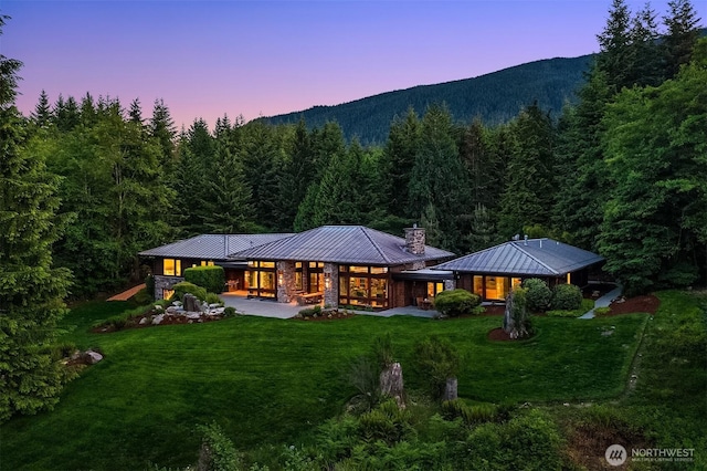 15910 Uplands Way SE, North Bend, WA 98045 - rear view of property featuring a standing seam roof, a view of trees, a chimney, and metal roof