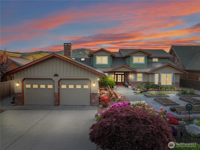 127 Bella Ln, Manson, WA 98831 - view of front facade with a garage, driveway, brick siding, a vegetable garden, and a chimney