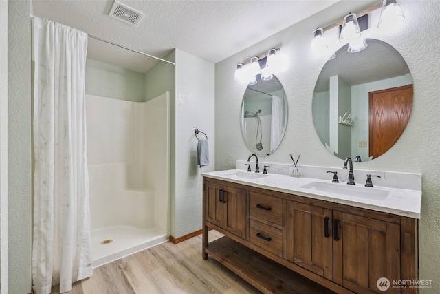 13820 Logez Ct SW, Olympia, WA 98512 - full bath with wood finished floors, double vanity, a shower with shower curtain, a textured ceiling, and a textured wall