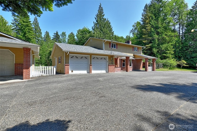 26025 Tronson Rd, Arlington, WA 98223 - view of front of house with brick siding, a garage, driveway, and a chimney
