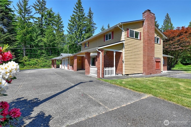 26025 Tronson Rd, Arlington, WA 98223 - view of front of home with a chimney, brick siding, asphalt driveway, and an attached garage