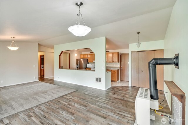 546 Canal Dr NE, Ocean Shores, WA 98569 - kitchen with stainless steel refrigerator with ice dispenser, light wood-type flooring, vaulted ceiling, pendant lighting, and baseboards
