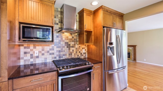 1931 237th St SE, Bothell, WA 98021 - kitchen with stainless steel appliances, wall chimney exhaust hood, dark stone countertops, backsplash, and brown cabinetry