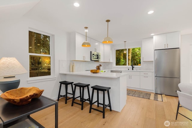 5613 43rd Ave NE, Seattle, WA 98105 - kitchen featuring appliances with stainless steel finishes, light wood-type flooring, tasteful backsplash, light countertops, and recessed lighting