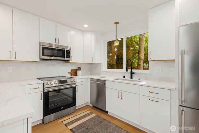 5613 43rd Ave NE, Seattle, WA 98105 - kitchen with appliances with stainless steel finishes, a sink, light wood-style flooring, white cabinetry, and pendant lighting