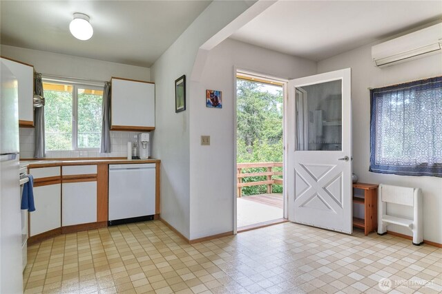 669 Marine Dr, Point Roberts, WA 98281 - kitchen with dishwasher, an AC wall unit, white cabinetry, baseboards, and healthy amount of natural light