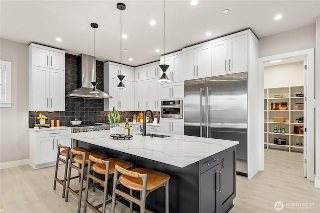 203 8th Ave W, Kirkland, WA 98033 - kitchen with wall chimney range hood, appliances with stainless steel finishes, light wood-style floors, a sink, and light stone counters