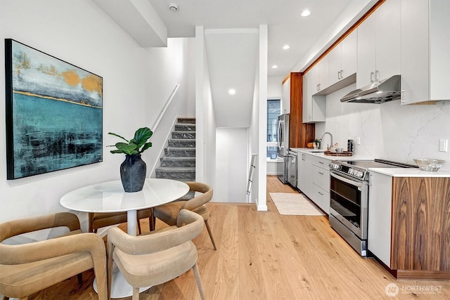 1225 E Roy St, Seattle, WA 98102 - kitchen with under cabinet range hood, appliances with stainless steel finishes, light countertops, light wood-type flooring, and recessed lighting
