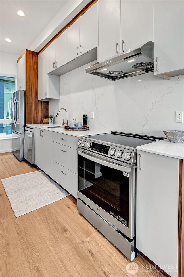 1225 E Roy St, Seattle, WA 98102 - kitchen featuring appliances with stainless steel finishes, under cabinet range hood, light countertops, a sink, and recessed lighting
