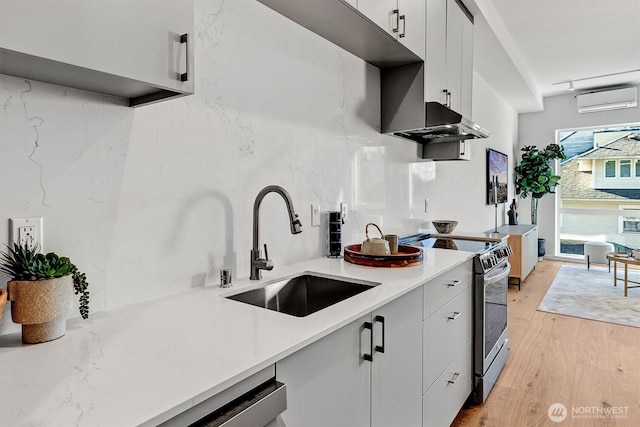 1225 E Roy St, Seattle, WA 98102 - kitchen with stainless steel range with electric stovetop, a sink, an AC wall unit, light wood-style flooring, and light countertops