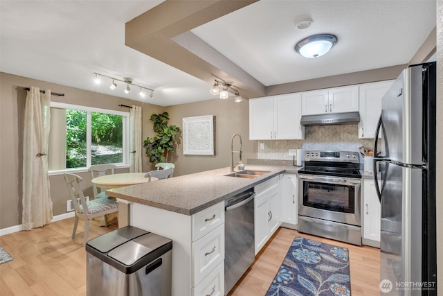 4231 NE 5th St Unit E101, Renton, WA 98059 - kitchen with stainless steel appliances, under cabinet range hood, a peninsula, white cabinets, and rail lighting