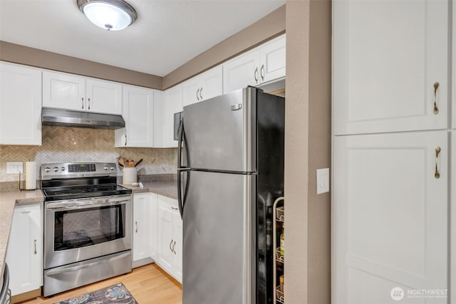 4231 NE 5th St Unit E101, Renton, WA 98059 - kitchen with appliances with stainless steel finishes, under cabinet range hood, white cabinetry, backsplash, and light wood-style floors