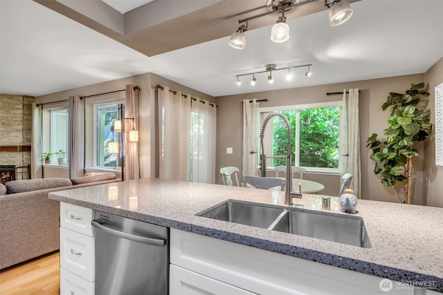 4231 NE 5th St Unit E101, Renton, WA 98059 - kitchen featuring dishwasher, white cabinets, light stone counters, a fireplace, and light wood-type flooring