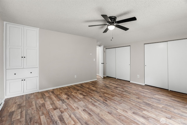 4562 SE Burley Olalla Rd, Olalla, WA 98359 - unfurnished bedroom featuring a textured ceiling, wood finished floors, two closets, baseboards, and a ceiling fan