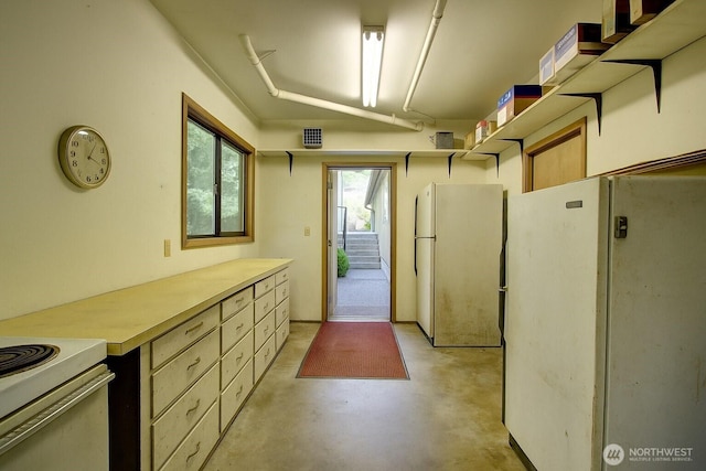 17147 Hope Island Ln, La Conner, WA 98257 - kitchen with freestanding refrigerator, concrete floors, and light countertops