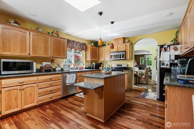 1440 Allyn Ln, Oak Harbor, WA 98277 - kitchen featuring appliances with stainless steel finishes, arched walkways, a center island, wood finished floors, and a sink