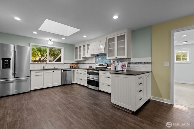 1716 N 125th St, Seattle, WA 98133 - kitchen featuring appliances with stainless steel finishes, custom exhaust hood, a skylight, dark countertops, and backsplash