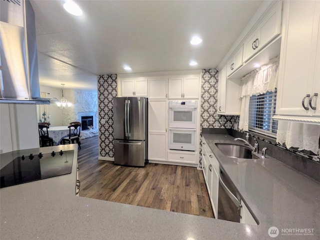 201 Union Ave SE Unit 188, Renton, WA 98059 - kitchen with appliances with stainless steel finishes, a sink, island range hood, white cabinetry, and a chandelier