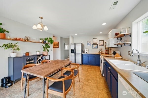 252 NW Ruby Ln, College Place, WA 99324 - kitchen featuring blue cabinets, stainless steel refrigerator with ice dispenser, open shelves, a sink, and a chandelier