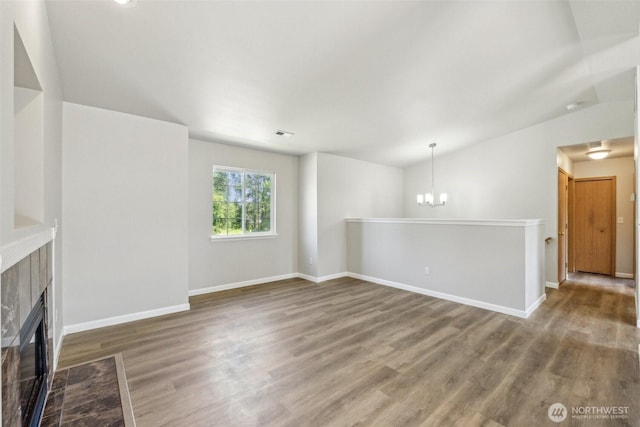 324 E 48th Street Dr, Tacoma, WA 98404 - unfurnished living room with a tiled fireplace, wood finished floors, a chandelier, baseboards, and vaulted ceiling