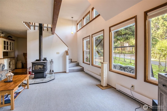 24 Nancy Ln, Copalis Beach, WA 98535 - unfurnished living room featuring light carpet, baseboard heating, stairway, a wood stove, and beamed ceiling