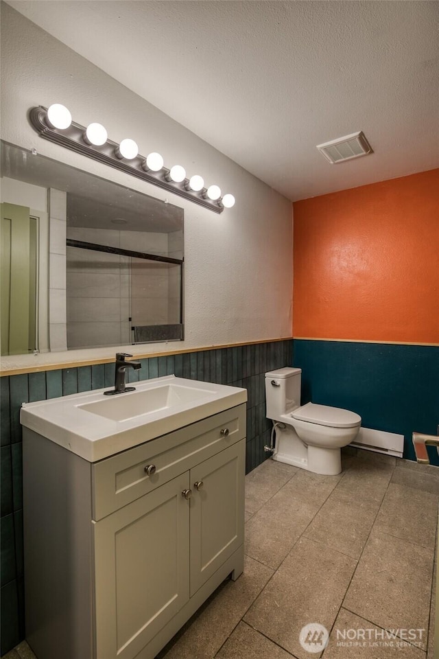 24 Nancy Ln, Copalis Beach, WA 98535 - full bath featuring a baseboard radiator, vanity, toilet, wainscoting, and a textured ceiling