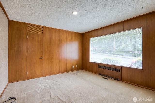 809 N K St, Aberdeen, WA 98520 - carpeted empty room with radiator heating unit, healthy amount of natural light, a textured ceiling, wooden walls, and baseboards