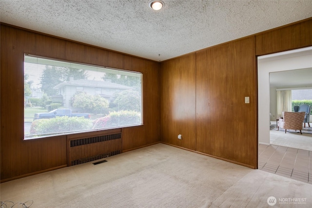 809 N K St, Aberdeen, WA 98520 - spare room featuring radiator, wooden walls, carpet flooring, a textured ceiling, and tile patterned flooring