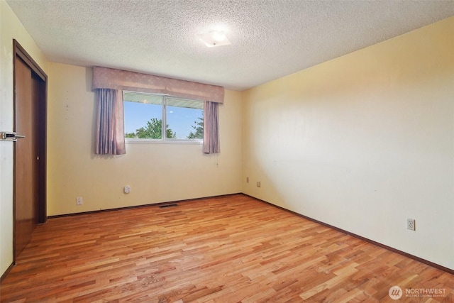 32427 6th Ave, Black Diamond, WA 98010 - unfurnished bedroom featuring light wood finished floors, a textured ceiling, and baseboards