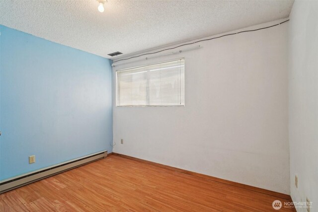 32427 6th Ave, Black Diamond, WA 98010 - unfurnished room featuring baseboard heating, a textured ceiling, light wood-style floors, and baseboards
