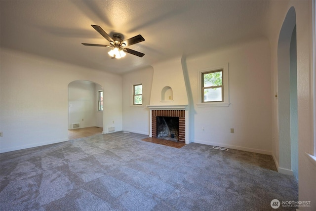 1030 N Clinton St, Walla Walla, WA 99362 - unfurnished living room with arched walkways, ceiling fan, a fireplace, and carpet flooring