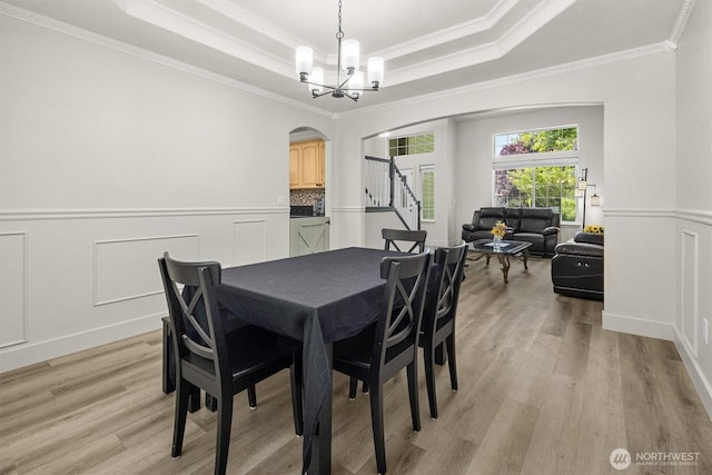13901 Cedar Ct, Sultan, WA 98294 - dining area featuring arched walkways, stairs, crown molding, a raised ceiling, and light wood-style flooring