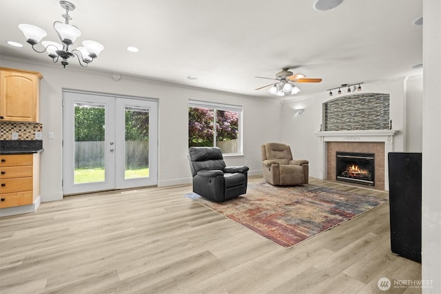 13901 Cedar Ct, Sultan, WA 98294 - sitting room featuring french doors, a fireplace, light wood-style flooring, a ceiling fan, and a chandelier