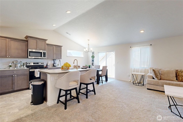 7 Patty Cir, Milton-Freewater, OR 97862 - kitchen with appliances with stainless steel finishes, lofted ceiling, a breakfast bar, a kitchen island with sink, and a chandelier