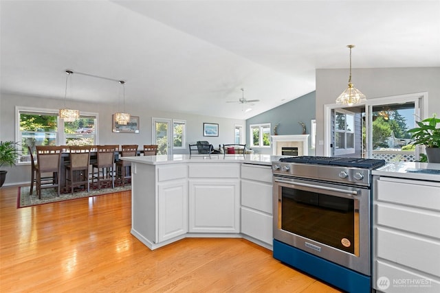 1022 S 225th Ln, Des Moines, WA 98198 - kitchen with stainless steel range with gas cooktop, light wood-style flooring, white cabinetry, and vaulted ceiling