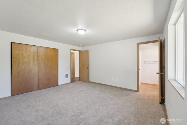 7115 239th Ct E, Graham, WA 98338 - unfurnished bedroom featuring light colored carpet, a closet, a textured ceiling, and baseboards