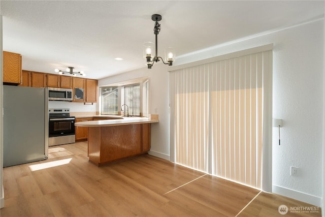 5201 S M St, Tacoma, WA 98408 - kitchen featuring stainless steel appliances, a chandelier, a peninsula, and light wood finished floors