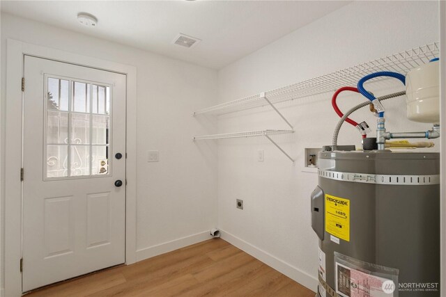 5201 S M St, Tacoma, WA 98408 - laundry area featuring strapped water heater, electric dryer hookup, light wood finished floors, washer hookup, and baseboards