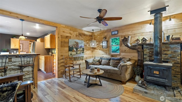 136 Tamarack Ln, Dayton, WA 99328 - living room featuring a wood stove, light wood-style floors, ceiling fan, and wood walls