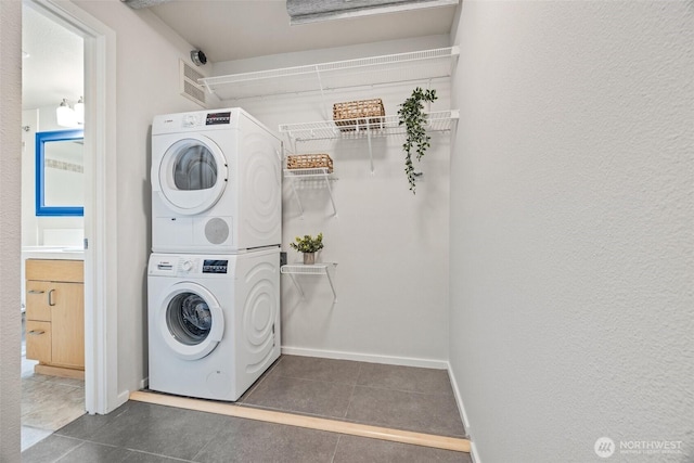 334 Lakeside Ave S Unit 404, Seattle, WA 98144 - laundry area with stacked washing machine and dryer, dark tile patterned floors, and baseboards