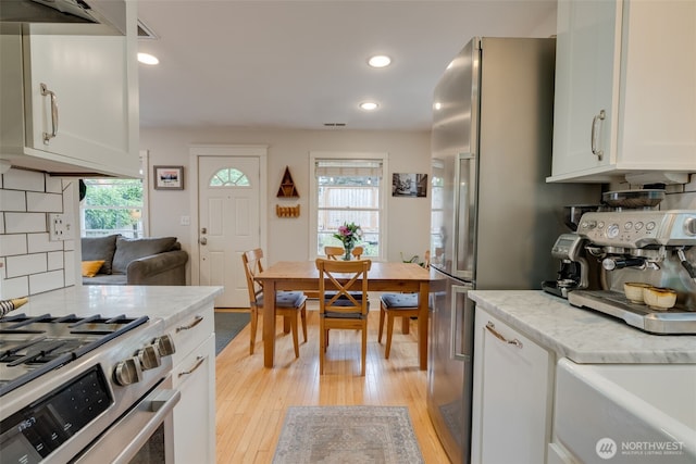 9741 Densmore Ave N, Seattle, WA 98103 - kitchen with plenty of natural light, light wood finished floors, white cabinets, stainless steel range with gas stovetop, and recessed lighting