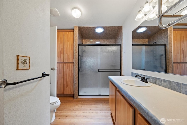 7220 E Belmont St, Othello, WA 99344 - bathroom with vanity, a stall shower, a textured wall, toilet, and wood finished floors