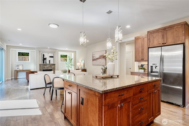 8910 125th Ln NE, Kirkland, WA 98033 - kitchen with stainless steel fridge with ice dispenser, a center island, light wood-type flooring, brown cabinetry, and recessed lighting