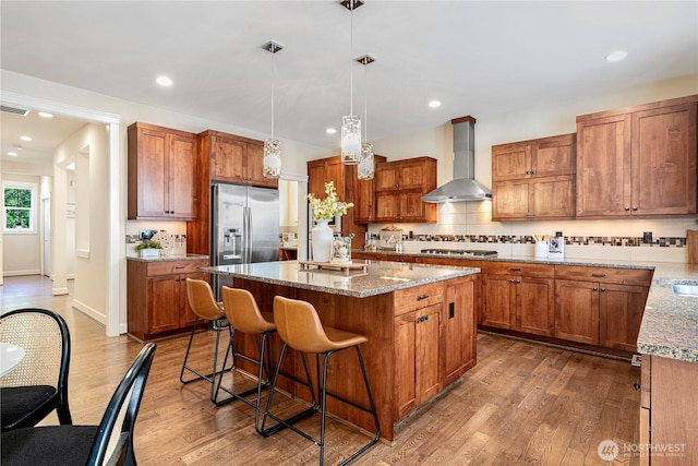 8910 125th Ln NE, Kirkland, WA 98033 - kitchen with wall chimney range hood, stainless steel appliances, a center island, a breakfast bar area, and brown cabinetry