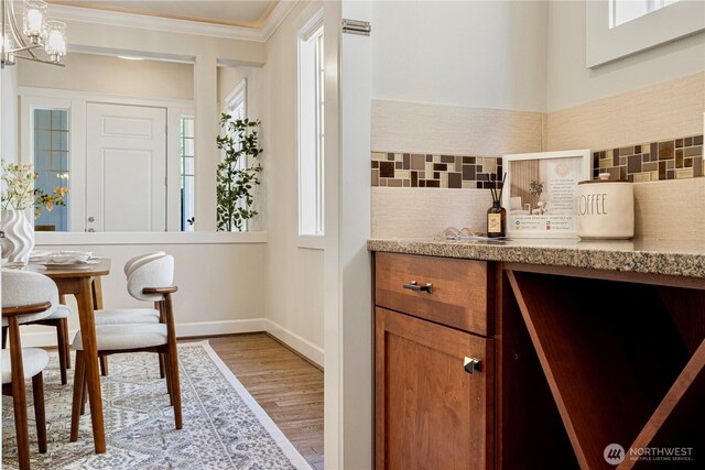 8910 125th Ln NE, Kirkland, WA 98033 - kitchen with decorative backsplash, crown molding, light wood-style floors, brown cabinetry, and light countertops