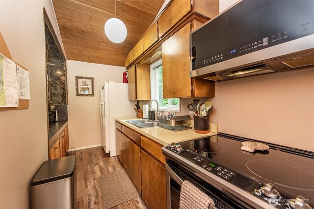 49 Sunny Point Ln, Port Angeles, WA 98363 - kitchen featuring electric stove, stainless steel microwave, brown cabinetry, a sink, and wood finished floors